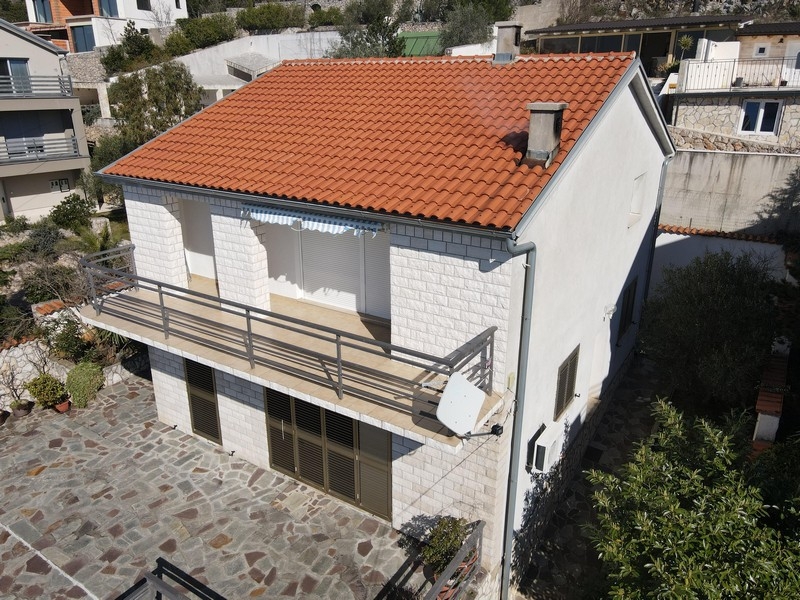 Casa con tetto in tegole e balcone sopra il cortile pavimentato