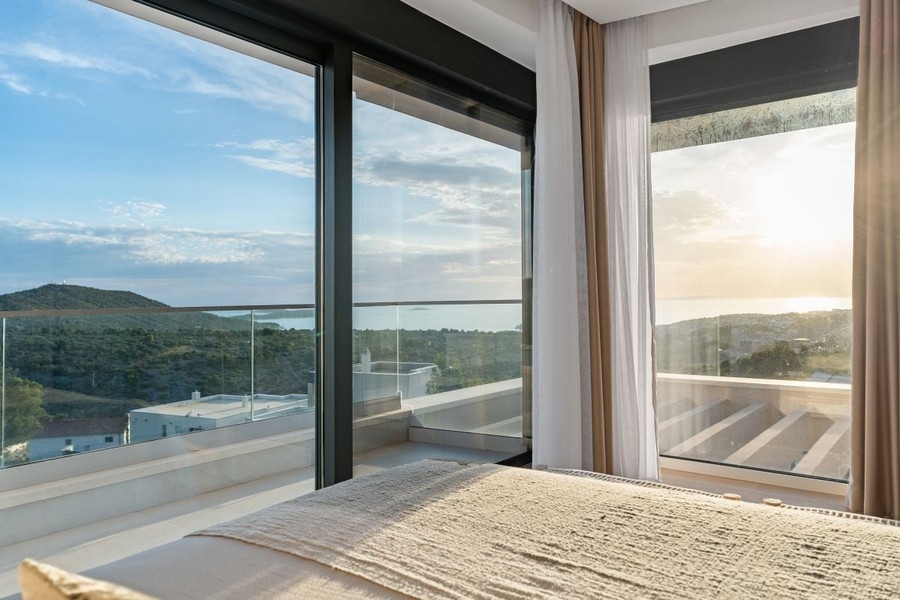 Camera da letto con finestre a tutta altezza e vista panoramica sul mare
