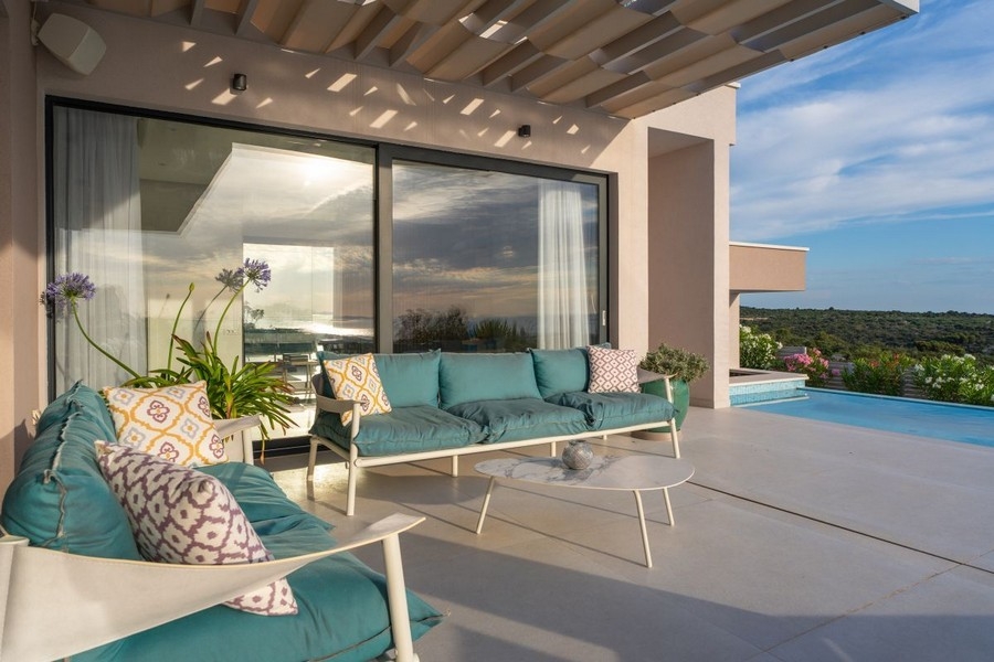 Terrazza coperta con lounge e vista su piscina e mare