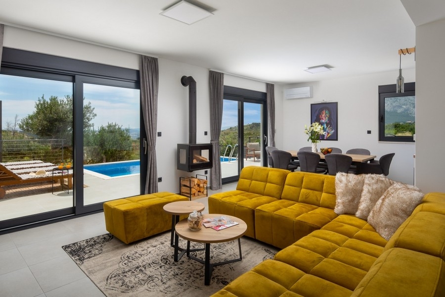 Zona giorno con divano, camino e accesso alla terrazza della piscina