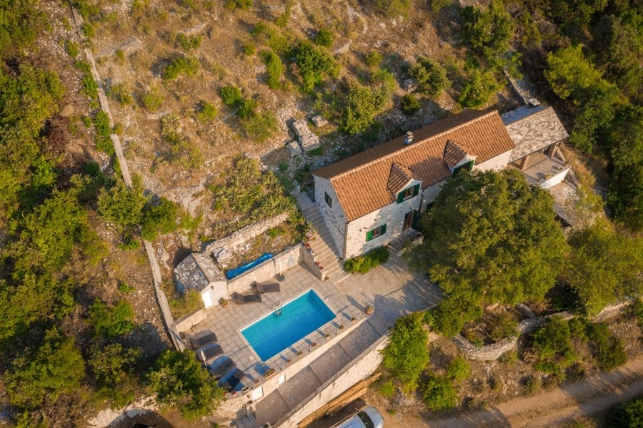 Vista aerea della casa in pietra con piscina sul pendio boscoso