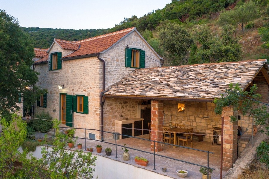 Casa in pietra con zona pranzo coperta sotto un tetto in lastre di pietra