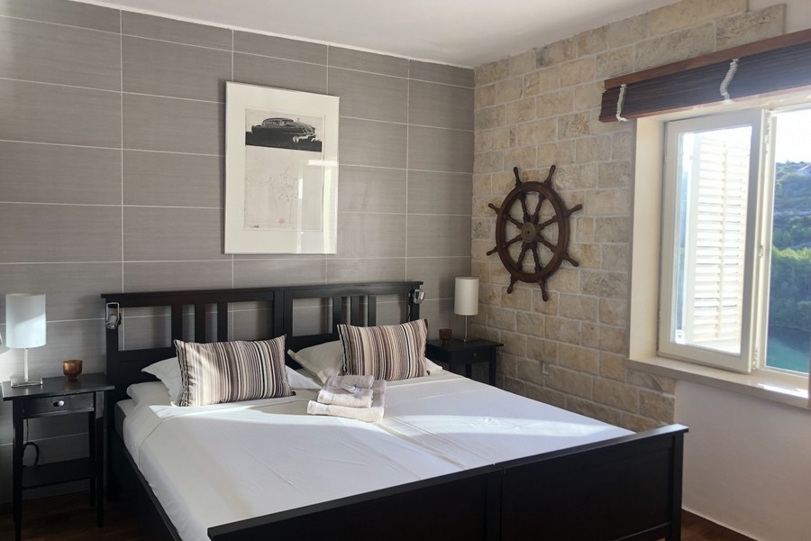 Camera da letto con parete in pietra e finestra con vista mare