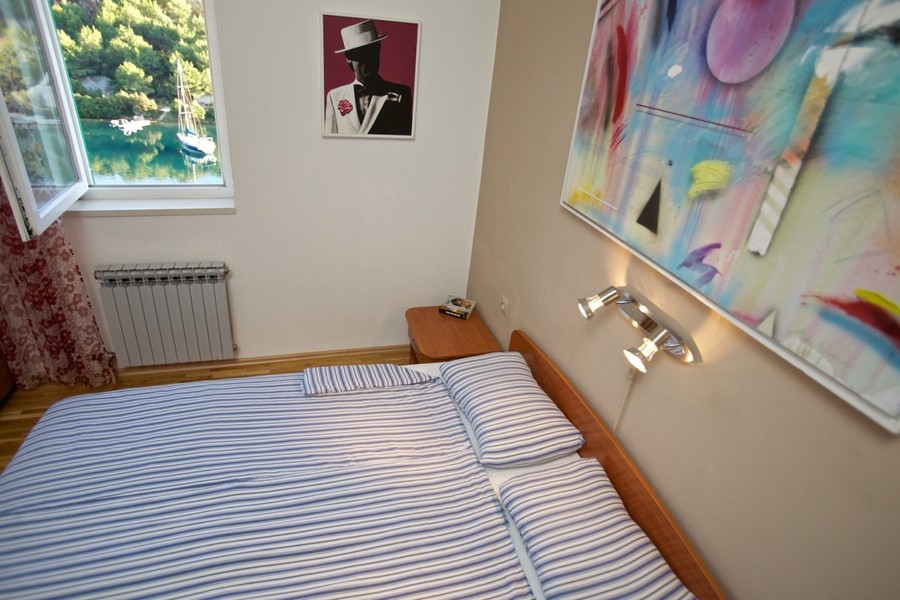 Camera da letto con vista dalla finestra sulla baia e su una barca a vela