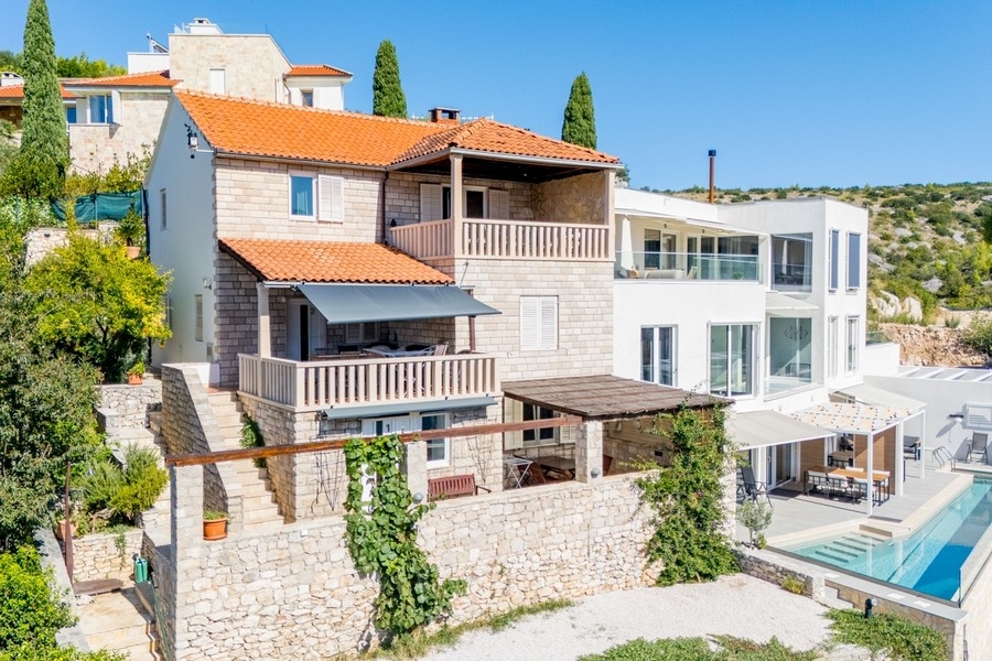 Casa in pietra con balconi accanto al nuovo edificio bianco con piscina