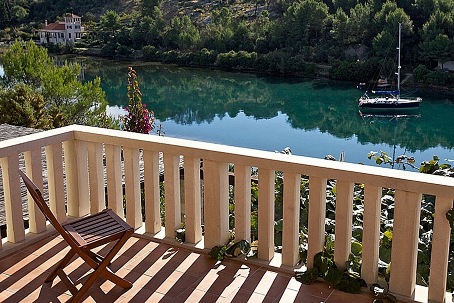 Balcone con vista sulla baia tranquilla e su una barca a vela