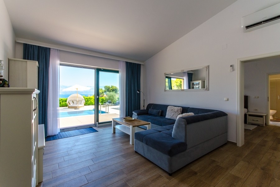 Zona giorno con divano e porta-finestra verso la piscina