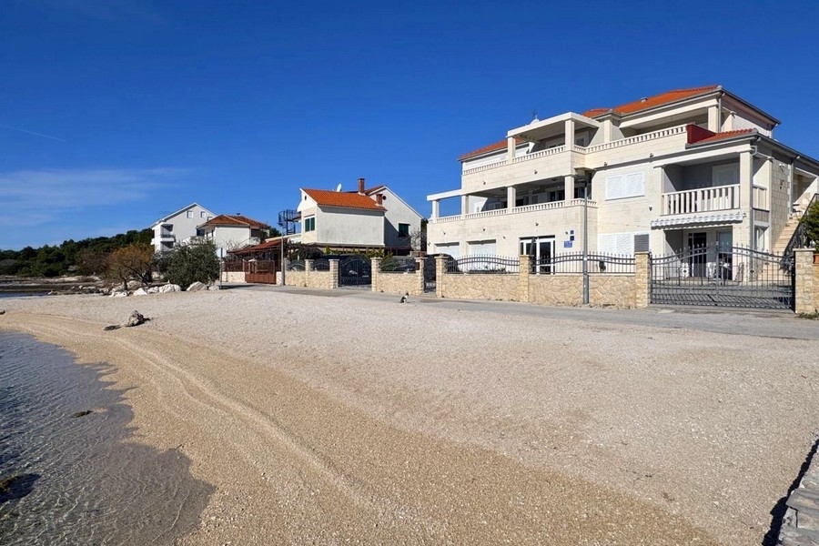 Casa con balconi sulla spiaggia di ghiaia sotto un cielo azzurro