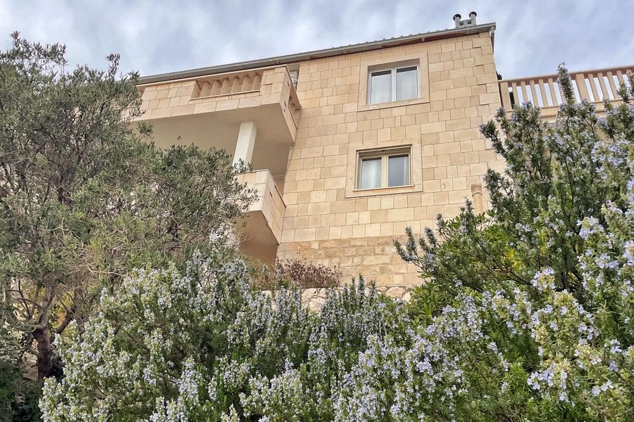 Facciata della casa in pietra naturale con balcone e giardino