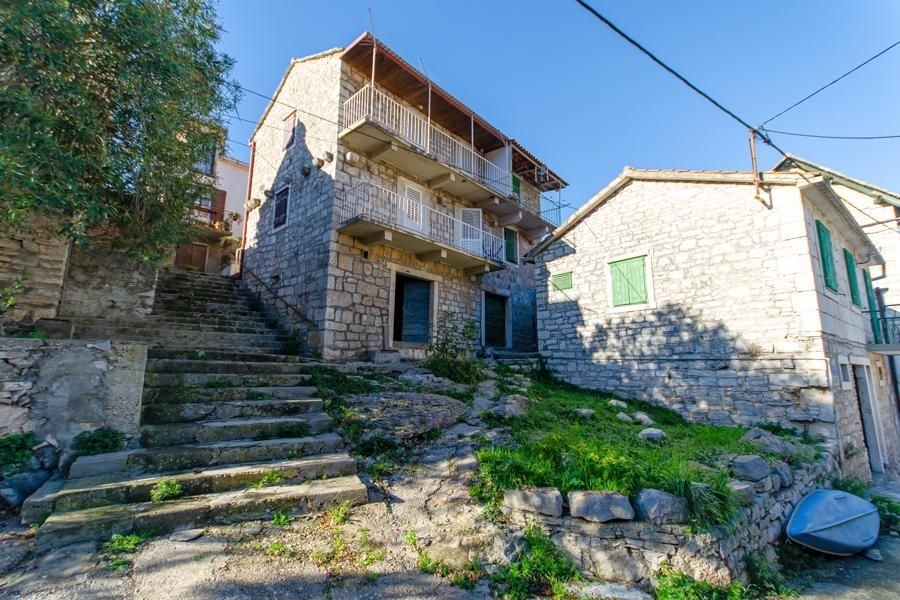 Vecchia casa in pietra con balconi in legno sopra la scalinata