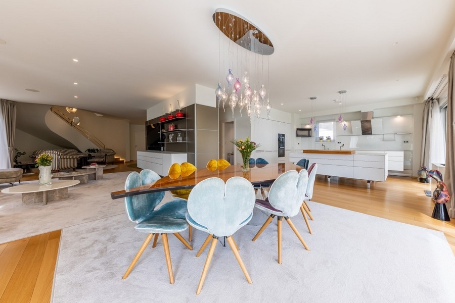 Zona pranzo aperta con lampada di design e cucina moderna