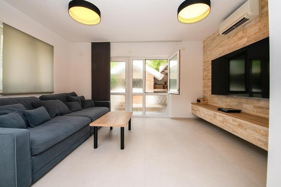 Soggiorno moderno con divano, parete TV e accesso alla terrazza