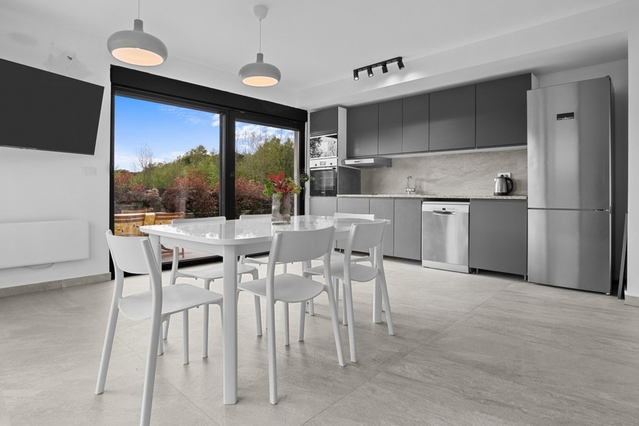 Zona giorno e pranzo moderna con cucina a vista e accesso alla terrazza