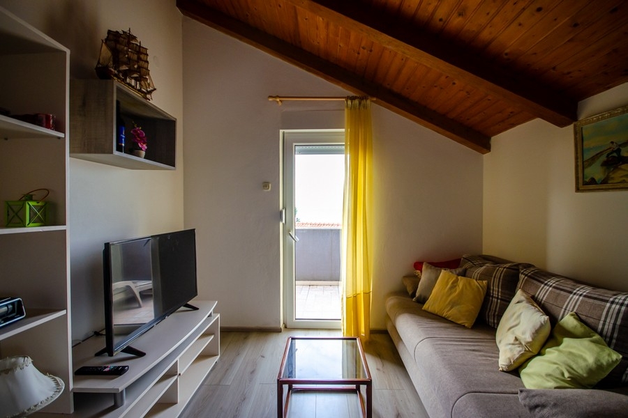 Soggiorno nel sottotetto con divano e accesso al balcone
