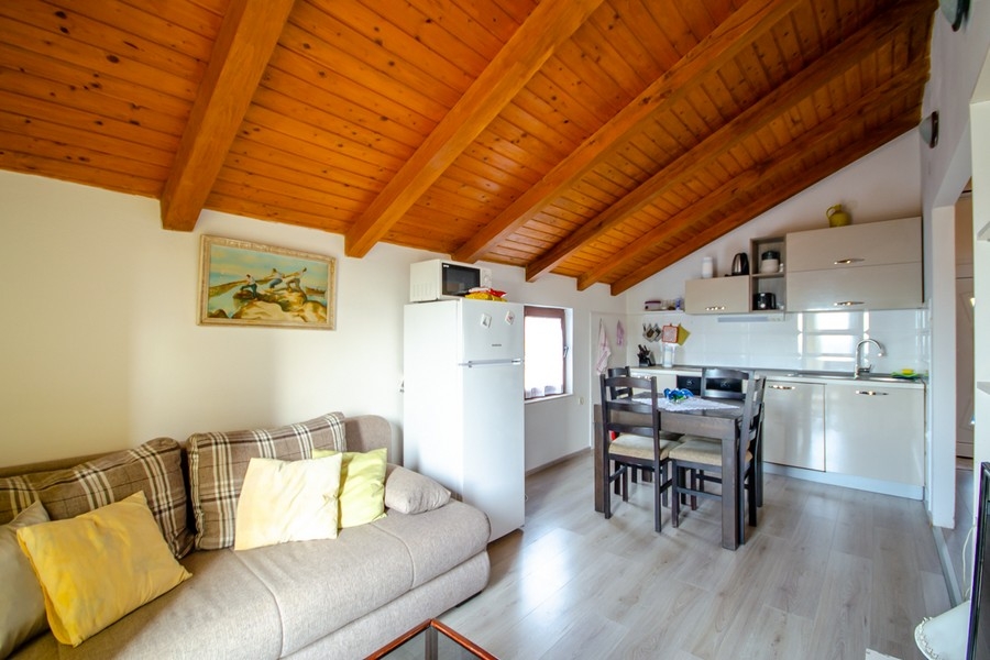Zona giorno e pranzo con cucina a vista e soffitto con travi in legno