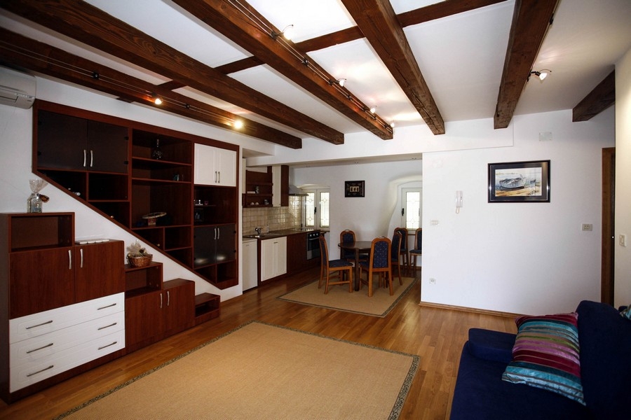 Soggiorno aperto con cucina su misura e soffitto in legno