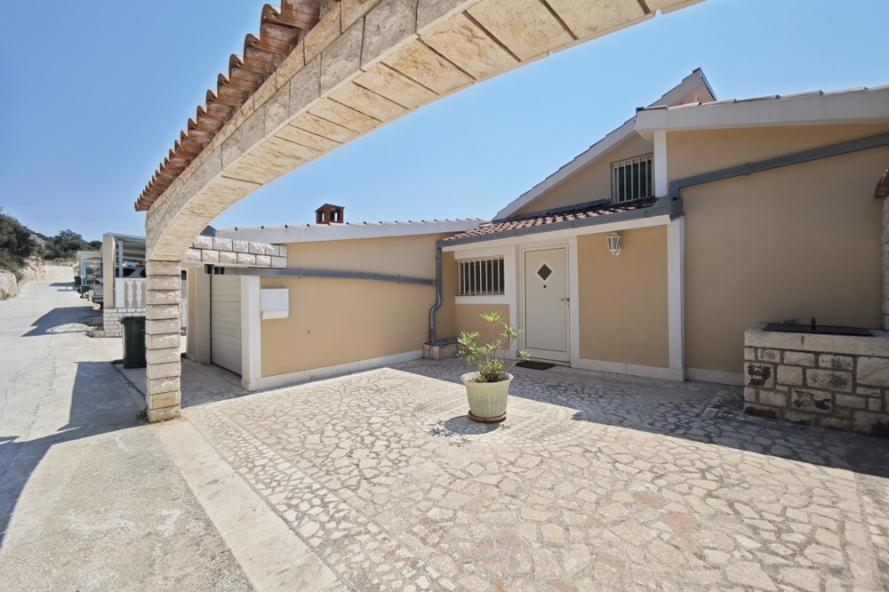 Facciata della casa con garage e cortile pavimentato