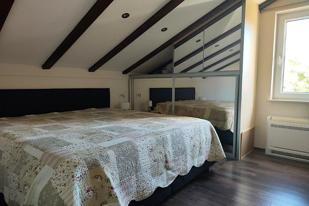Camera da letto nel sottotetto con travi in legno a vista