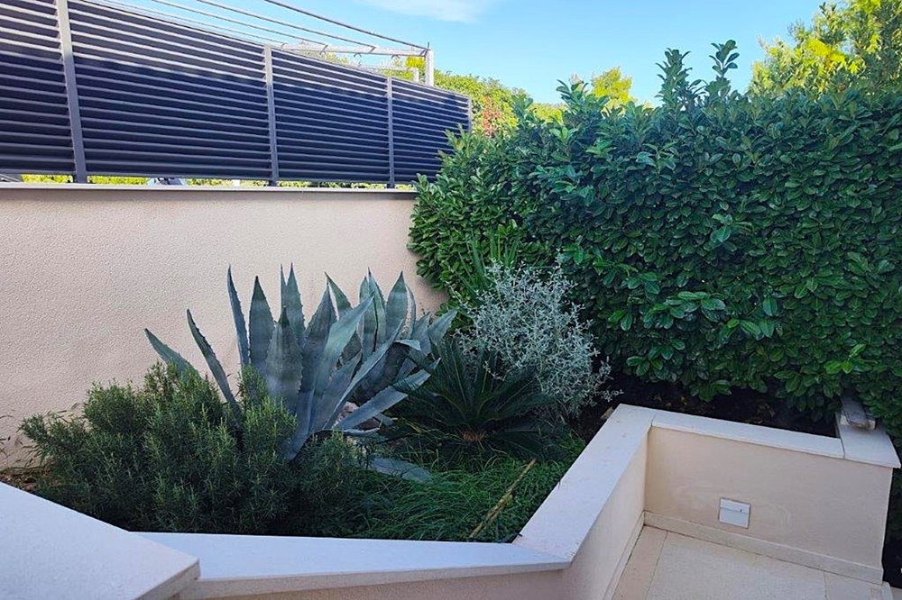 Area giardino con piantumazione mediterranea e muri in pietra