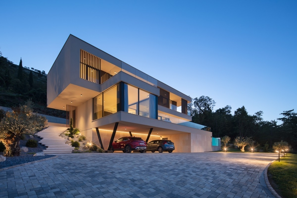 Villa illuminata con carport e cortile pavimentato di sera