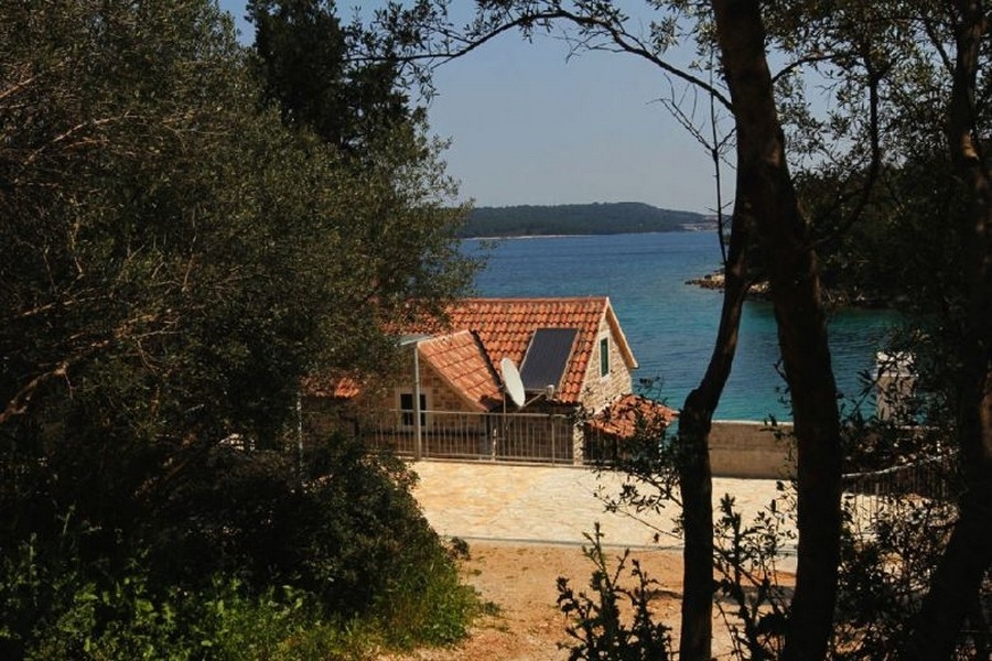 Casa in pietra con vista mare tra gli alberi