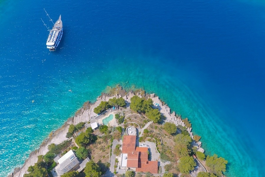 Veduta aerea della penisola con casa, piscina e battello per escursioni