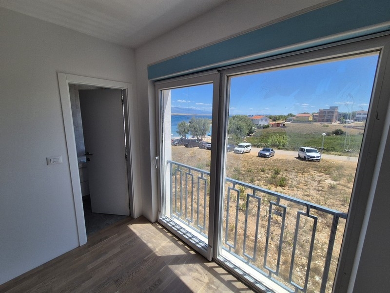 Camera da letto con grandi finestre e accesso a un balcone con vista mare.