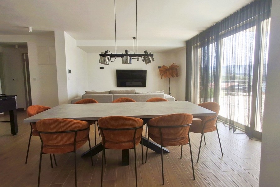 Zona pranzo luminosa con grandi vetrate e vista mare