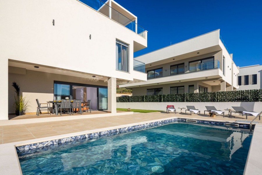 Piscina davanti alla casa con lettini da sole