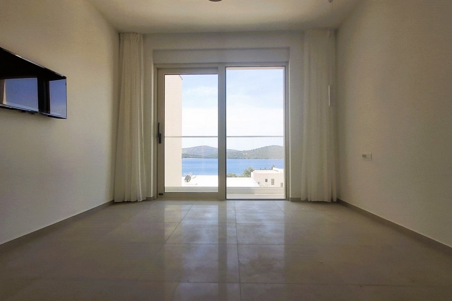 Stanza con televisore a parete e vista mare attraverso la porta in vetro