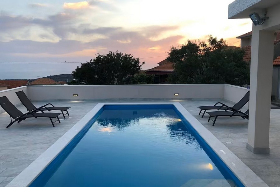 Piscina con sdraio e tramonto
