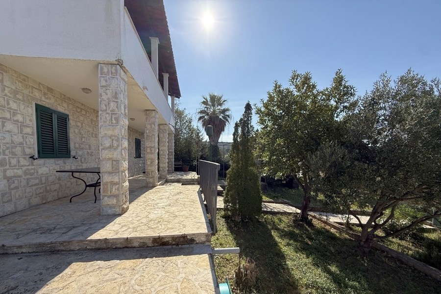 Vista della casa con facciata in pietra e giardino