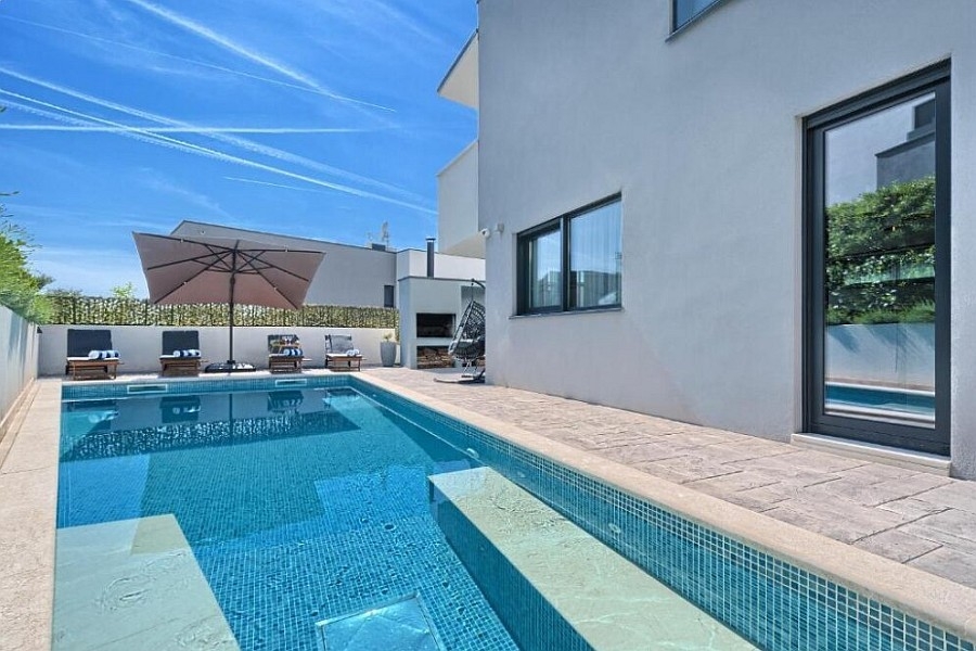 Piscina con ombrellone e sdraio presso la villa