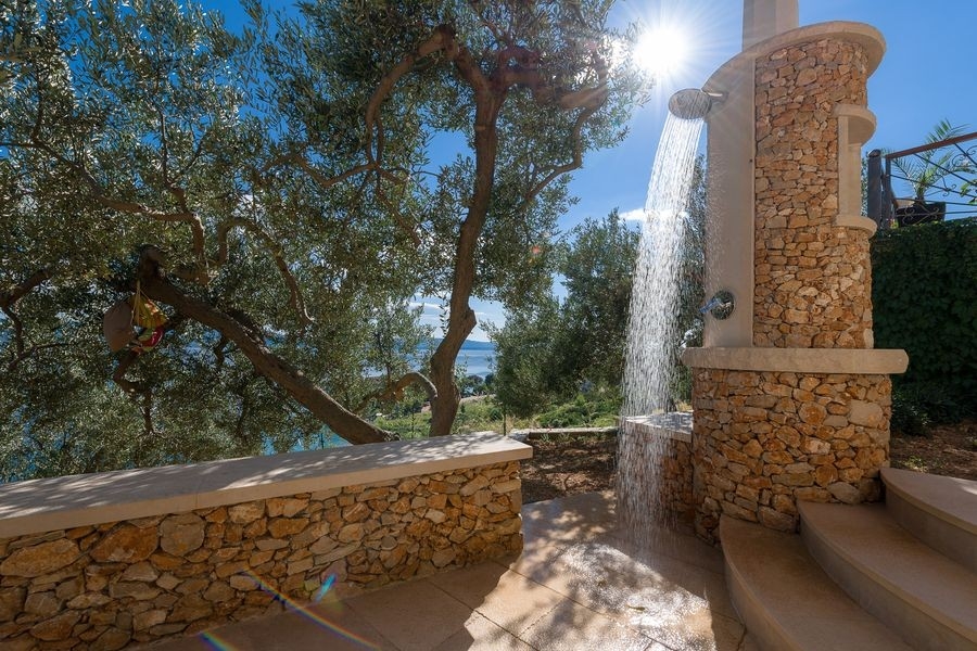 Doccia esterna presso un muro di pietra in giardino