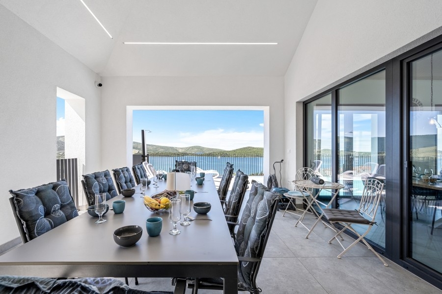 Zona pranzo luminosa con grande vetrata e vista mare