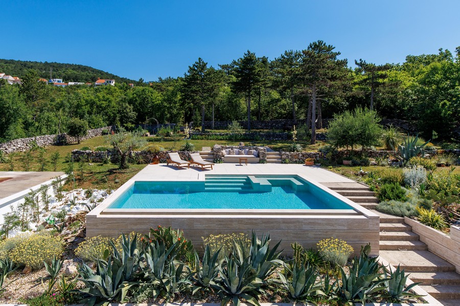 Piscina con lettini e giardino