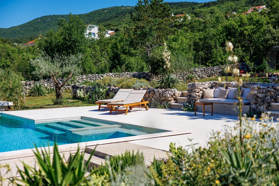 Zona piscina con lettini e giardino roccioso