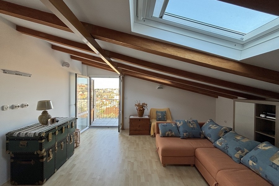 Zona giorno nel sottotetto con soffitto spiovente e travi in legno