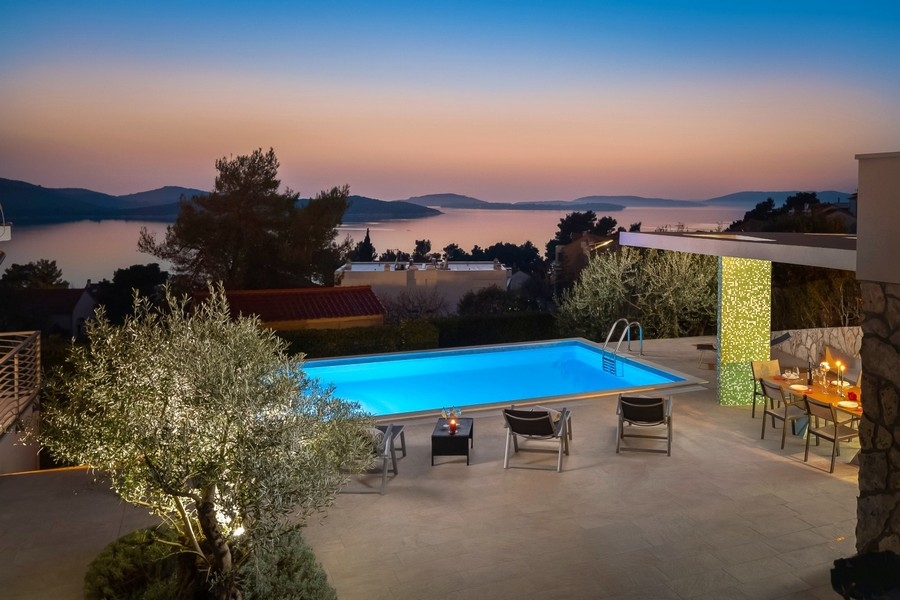 Piscina con cucina estiva e vista mare di sera
