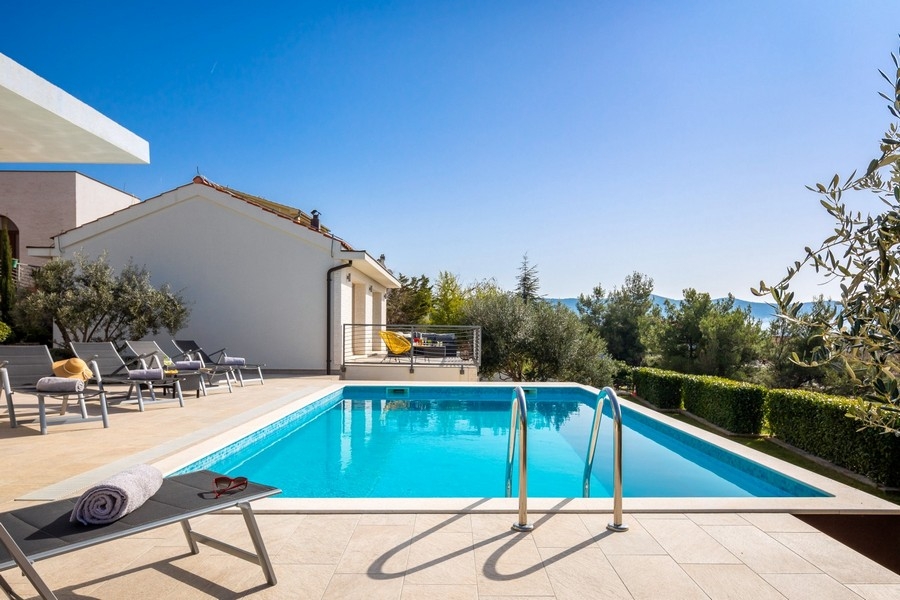 Piscina con lettini e vista mare