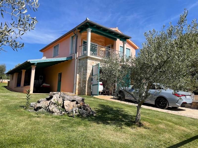 Vista della casa con posto auto coperto e giardino