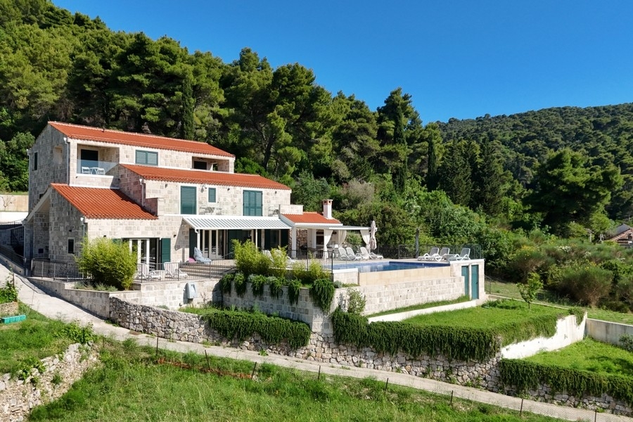 Villa con facciata in pietra, giardino e piscina