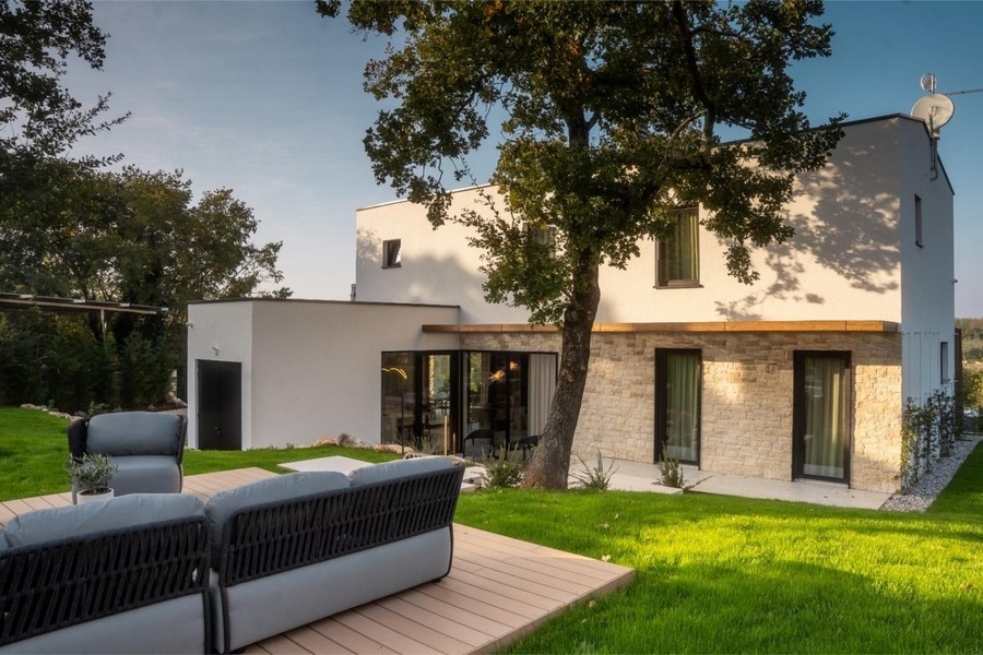 Villa con facciata in pietra e lounge su deck in legno