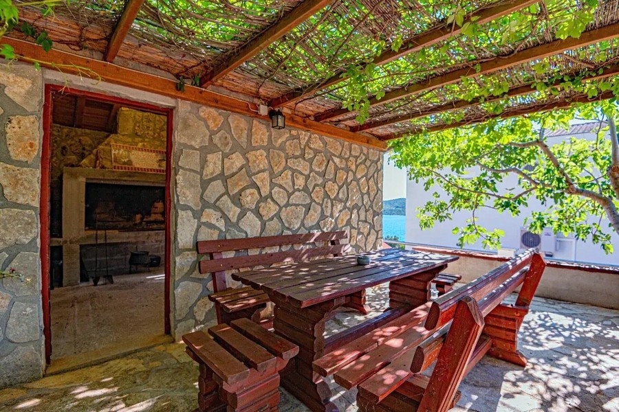 Cucina estiva coperta con grill e tavolo in legno