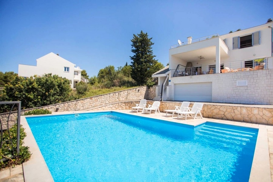 Grande piscina con lettini davanti alla villa