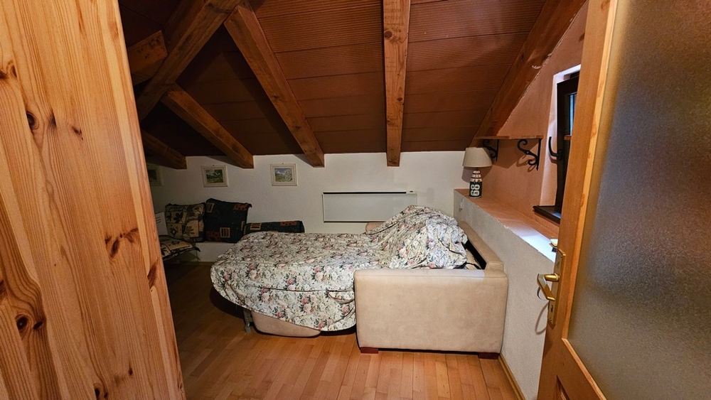 Camera mansardata con letto e travi in legno