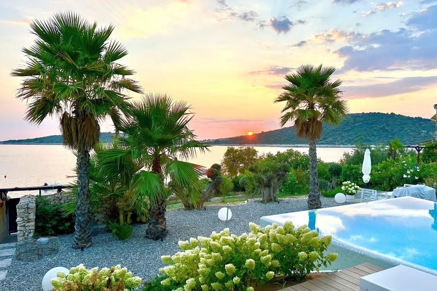 Tramonto sul mare con palme e piscina