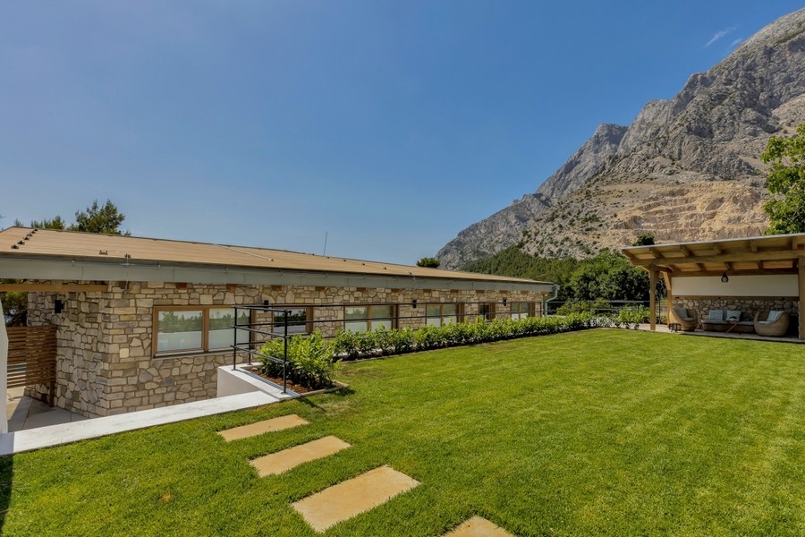 Prato davanti alla villa in pietra con sfondo di montagne