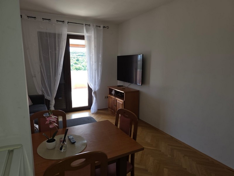 Zona giorno con tavolo, televisore e porta della terrazza