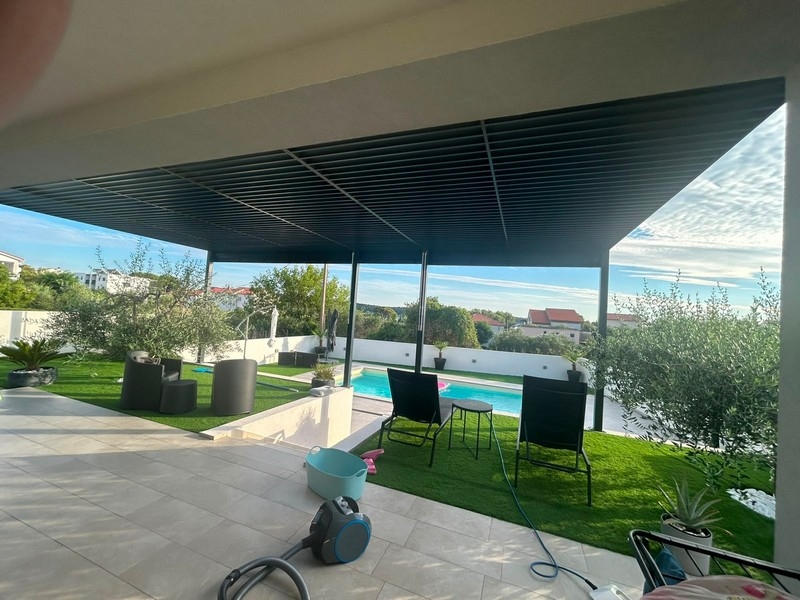 Terrazza coperta con salottino, prato e piscina